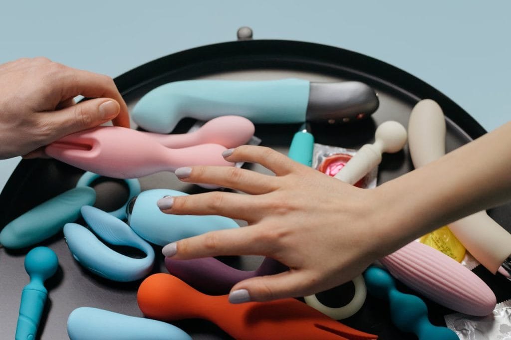 Adult Luxury vibrators and dildos sex toys An assortment of vibrant sex toys with hands reaching for selection.